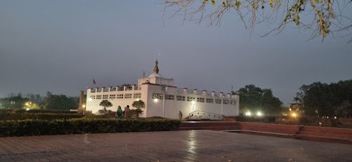 Vista panorâmica do Templo de Maya Devi, em Lumbini, refletido nas águas calmas do canal ao entardecer.