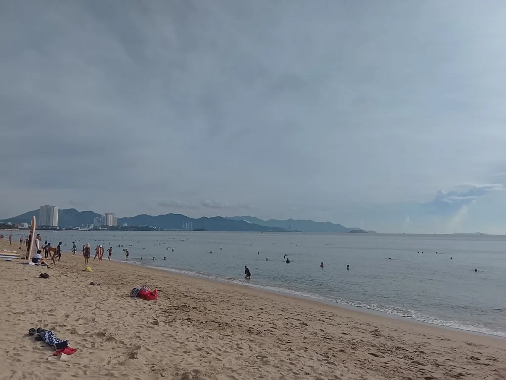 Praia de Nha Trang com mar calmo e faixa urbana, um dos principais pontos turísticos do litoral central do Vietnã.