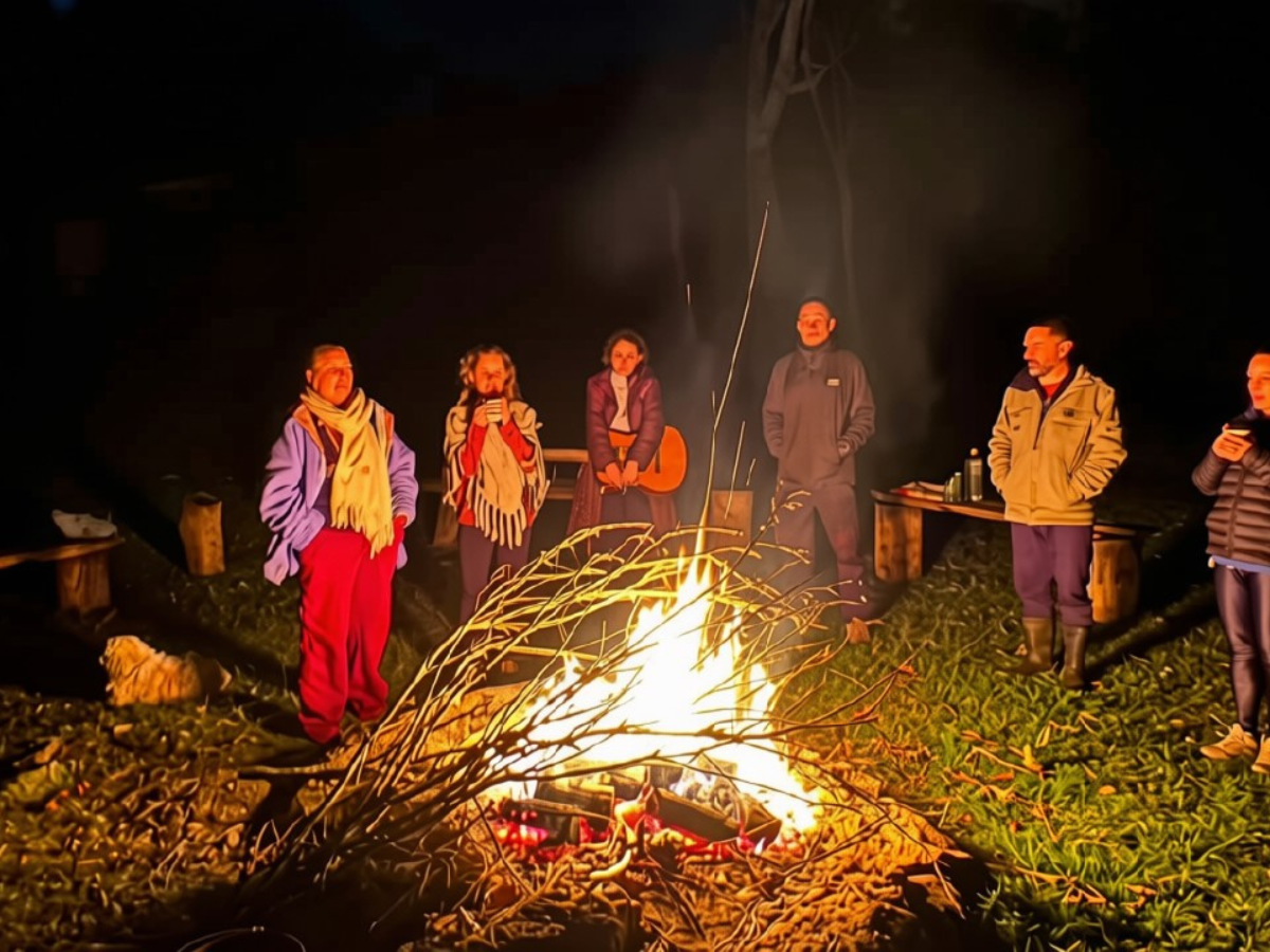Participantes do Retiro Travessias reunidos ao redor da fogueira durante a noite