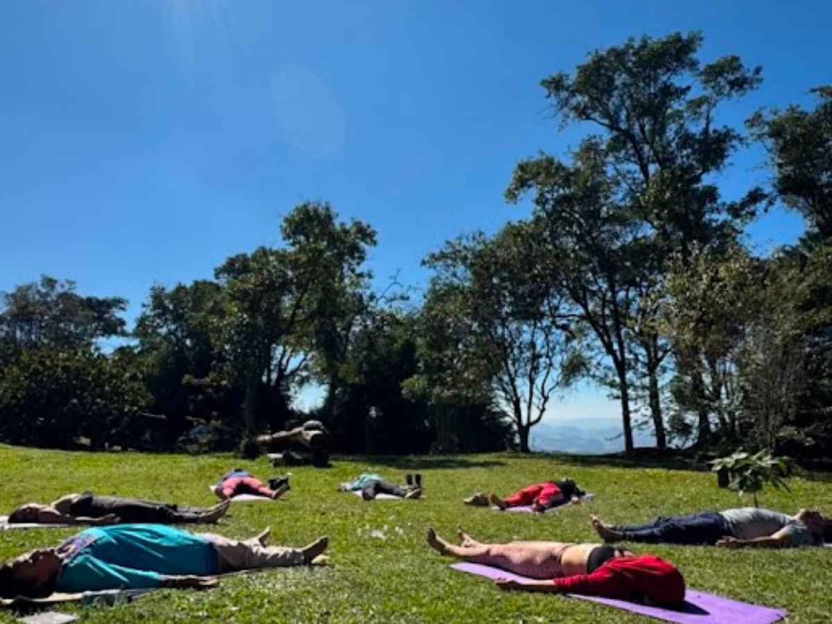 Participantes descansando em Shavasana no jardim durante um retiro da Trip.MySelf