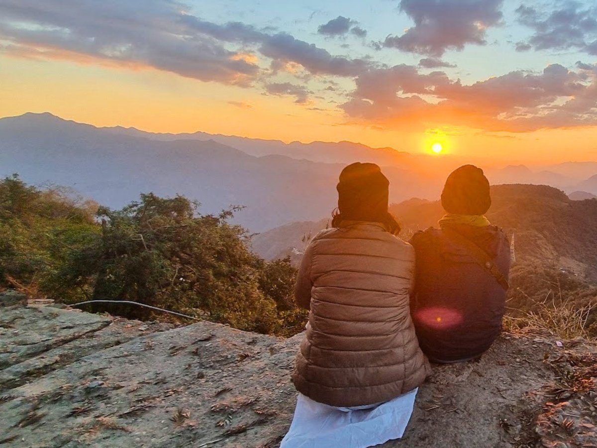 Duas pessoas contemplando o nascer do sol nas montanhas