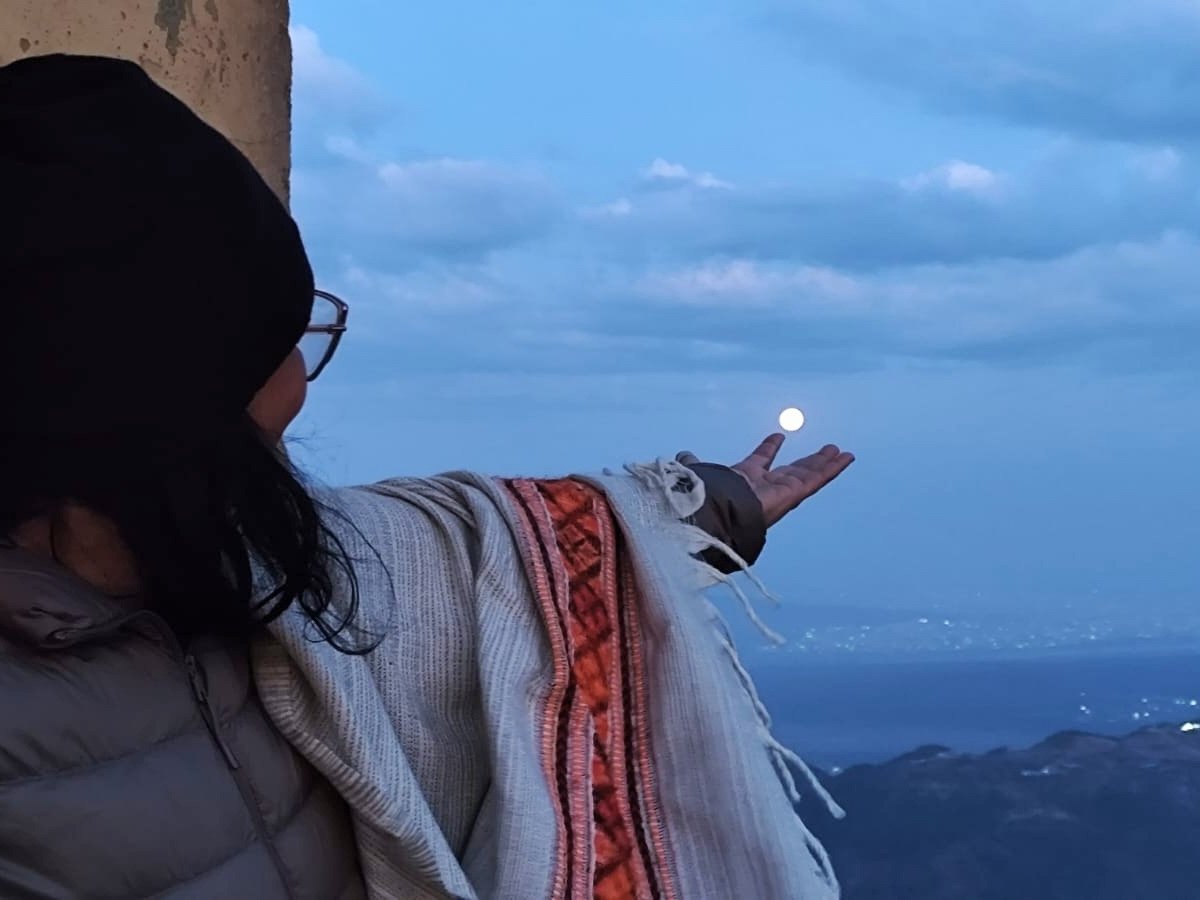 Pessoa com a mão voltada para o céu ao anoitecer